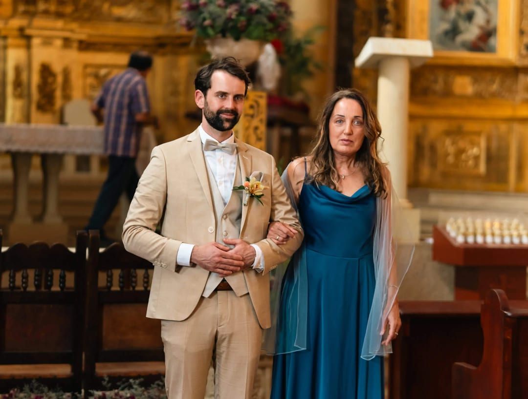 Groom, Alex, escorted by his mother in a church during Mariana & Alex's wedding.