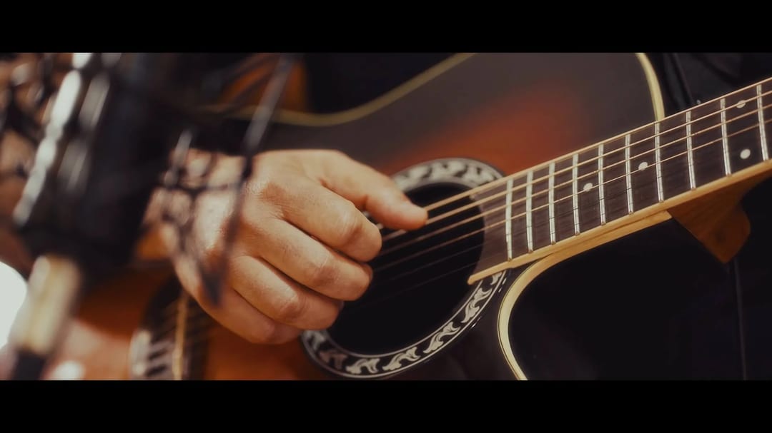 Close-up of a person playing an acoustic guitar, recording music