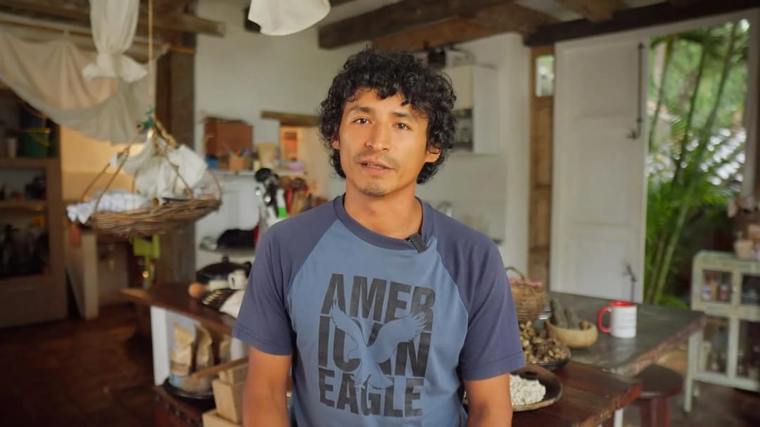 Un hombre con camiseta de American Eagle está de pie en una cocina rústica de Casa Común.