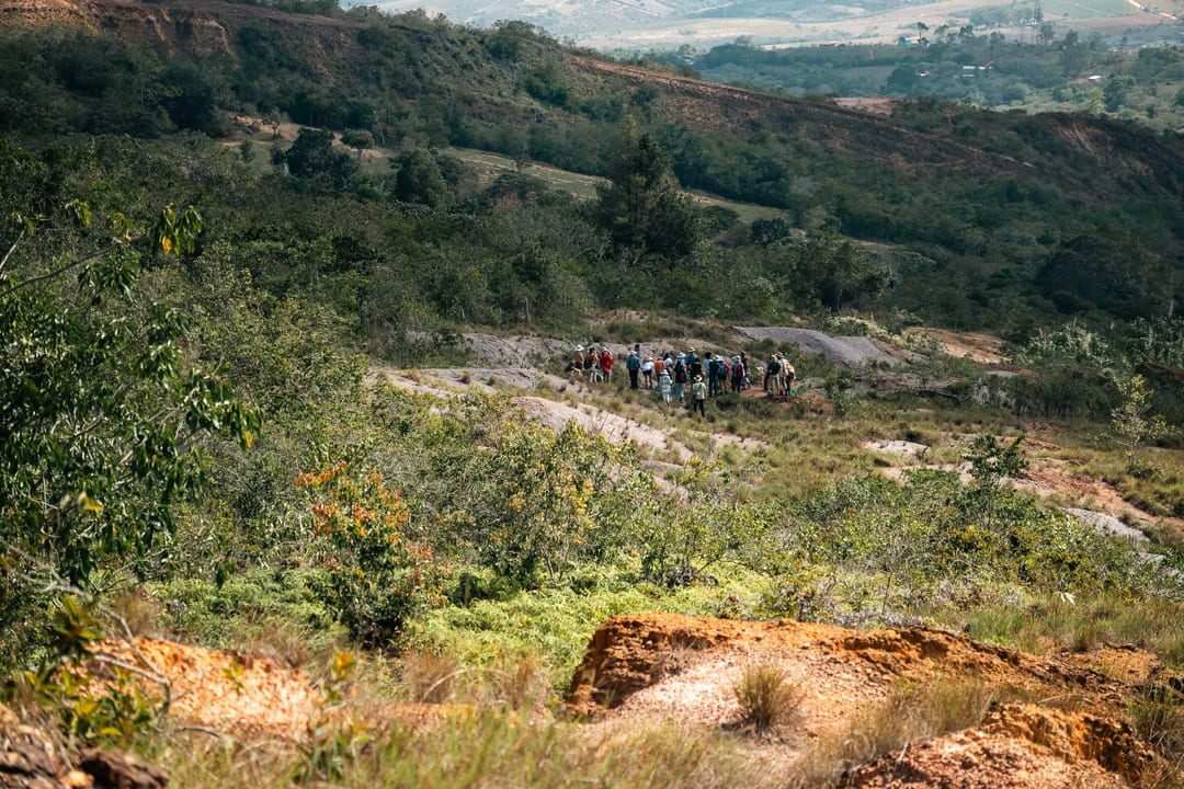 A group walks along a hillside surrounded by vegetation in rural Barichara.