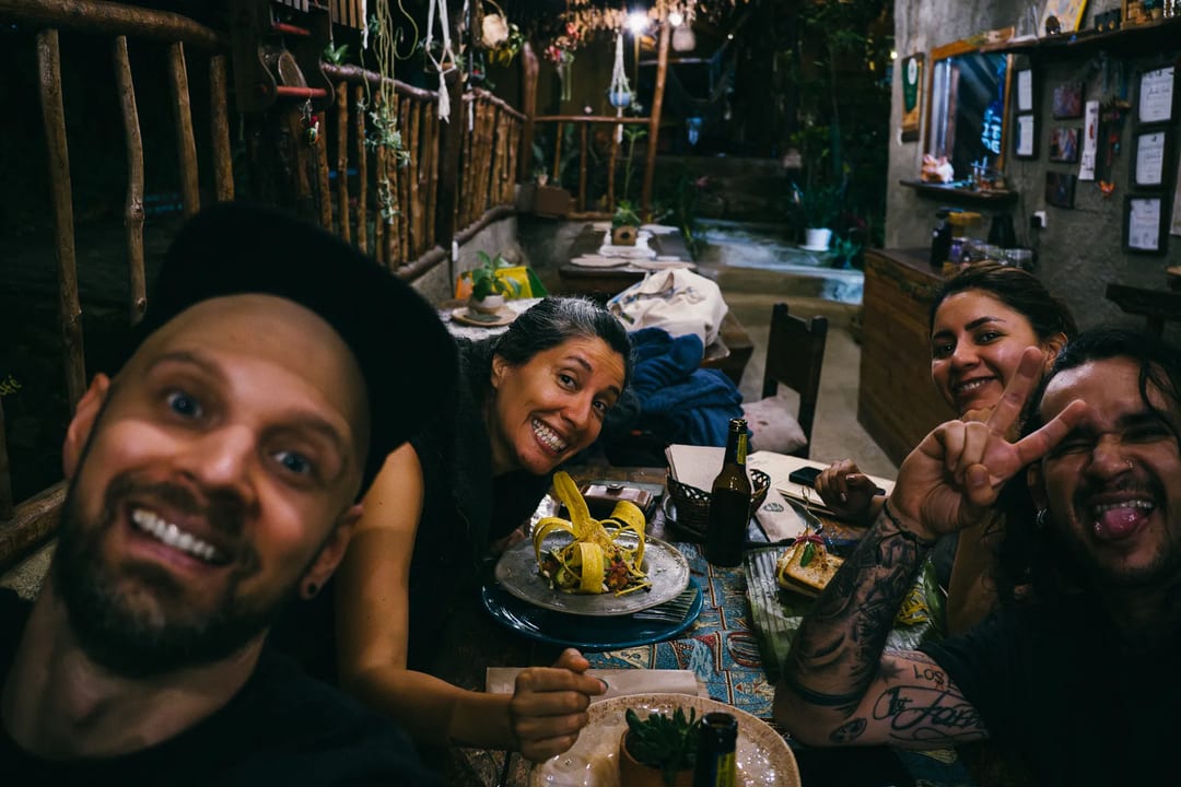Friends smiling at dinner with local food. El Páramo Weekend memories.