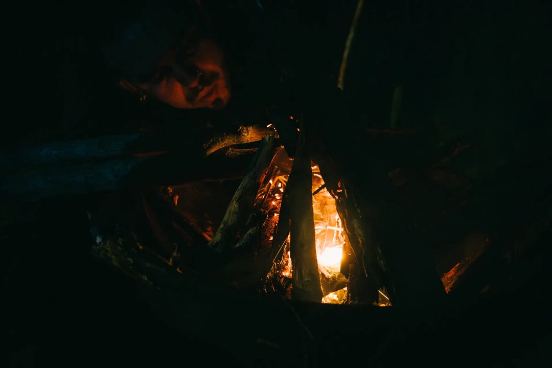Person watching a campfire burning in the dark. Camping in El Páramo.