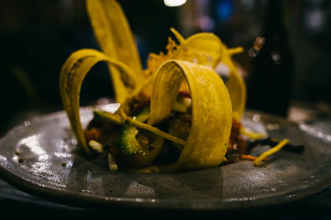 Plantain taco with avocado and salsa on a gray plate.